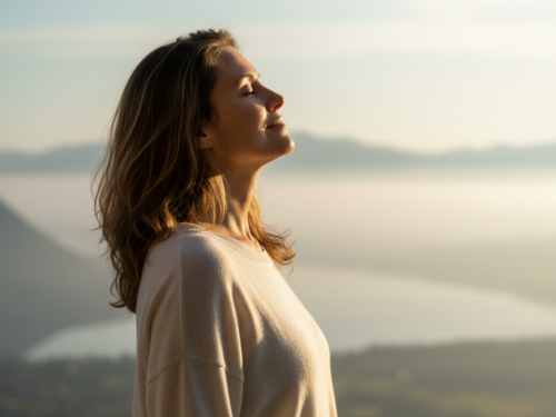 Frau im Sonnenaufgang mit Blick auf Berge und See, die innere Ruhe und Balance ausstrahlt – Symbol für Klarheit und Freiheit durch systemisches Coaching